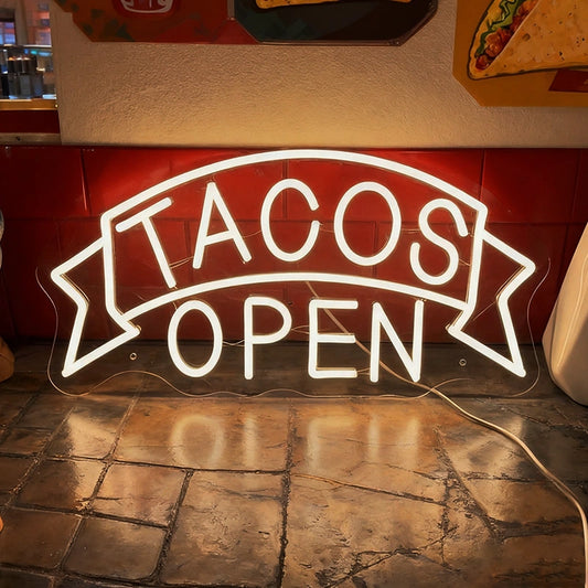 Glowing neon sign with 'TACOS OPEN' text in a mexican restaurant
