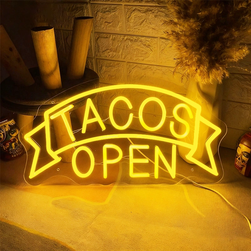 A glowing neon 'Tacos Open' sign in lemon yellow against a dark background.
