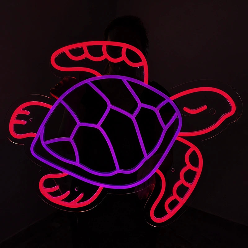 A glowing neon-style turtle sign with a purple shell outline and red outer body and flippers, shown against a dark background.