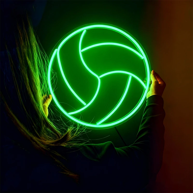 Person holding a glowing green volleyball against a dark background