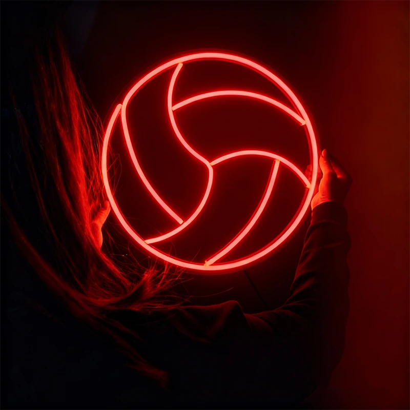 Person holding a glowing red volleyball neon sign against a dark background