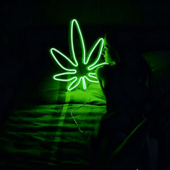 Women is watching at a green weed neon sign in a dark background.
