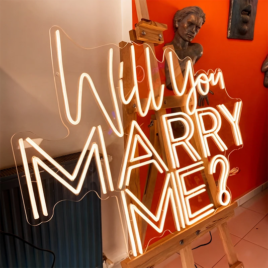 Neon sign asking 'Will you marry me?' in a room with sculptures and decor.