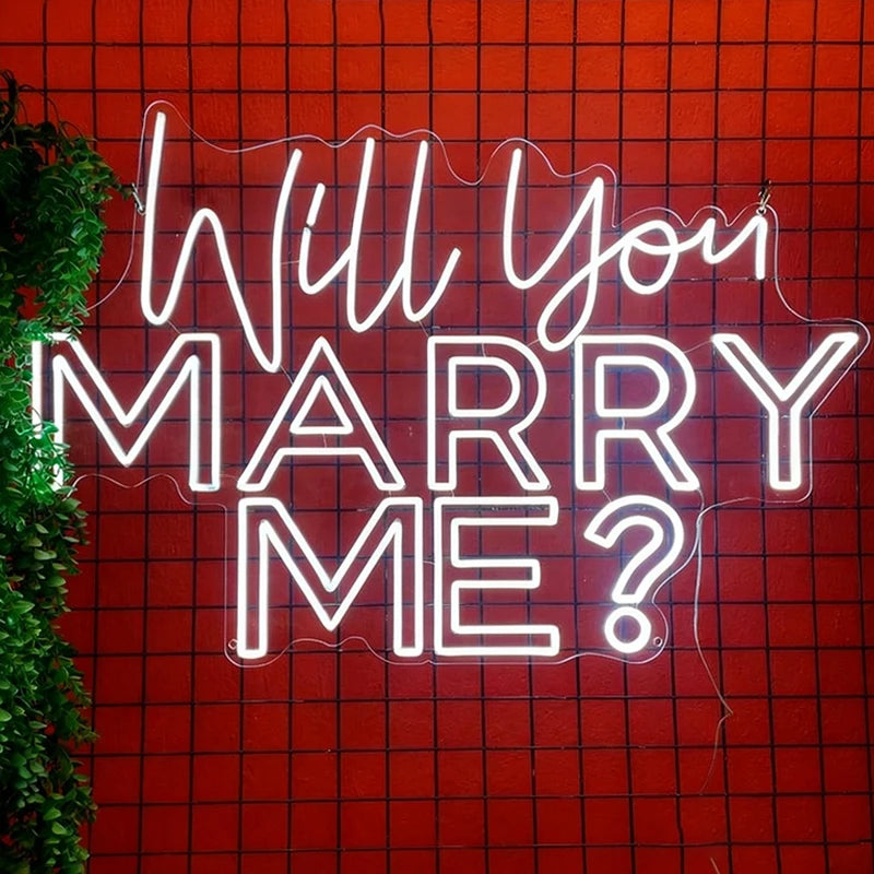 Neon sign with 'Will You Marry Me?' on a red grid background