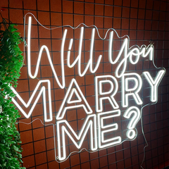 Neon sign on a tiled wall asking 'Will you marry me?'