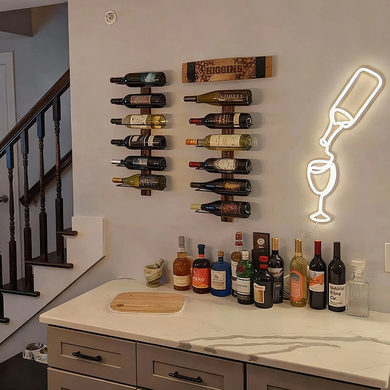 Wine bottles on a wall-mounted rack with a neon light shaped like a wine bottle and glass in a home setting.