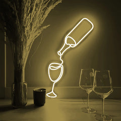 Neon light shaped like a wine bottle and glass on a dark background with two real wine glasses and a vase.