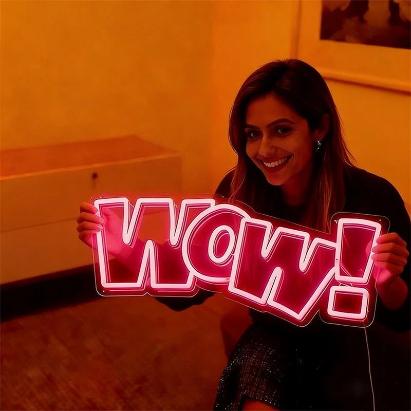 Person holding a neon sign with 'WOW!' in a warmly lit room.