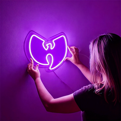 Person interacting with a neon Wu-Tang Clan logo on a purple wall