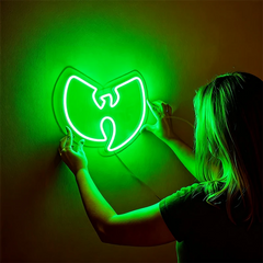 Person holding a green neon sign with a wu tang clan logo against a dark background