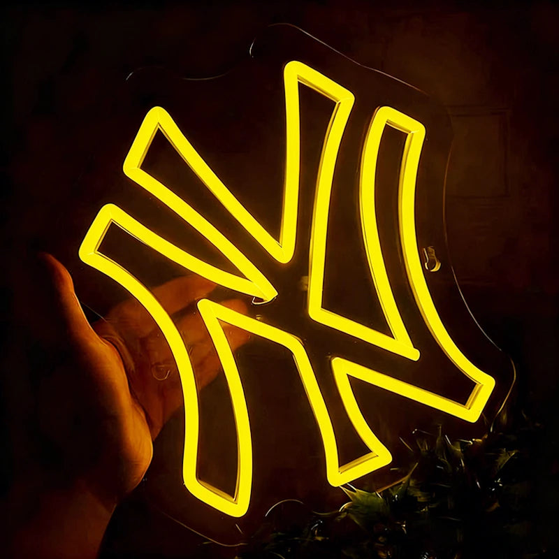 Neon lemon yellow light sign with a yankees-like design held by a hand against a dark background