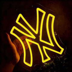 Neon lemon yellow light sign with a yankees-like design held by a hand against a dark background