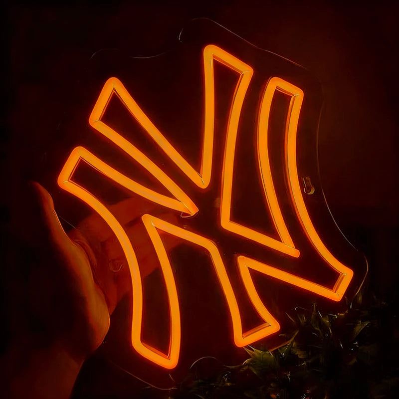 Neon orange light with a yankees logo, held by a hand against a dark background