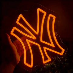 Neon orange light with a yankees logo, held by a hand against a dark background