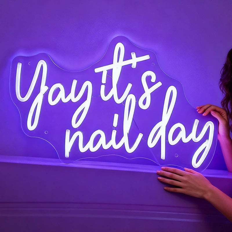 Neon purple light with 'Yay it's nail day' on a dark background