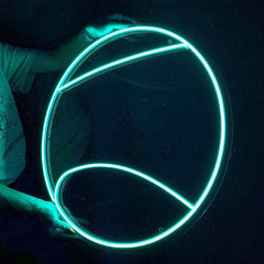 Person holding a glowing tennis ball neon sign against a dark background