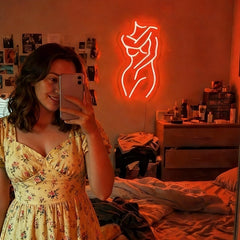 Neon sign of a woman on a wall in a bathroom with red lighting.